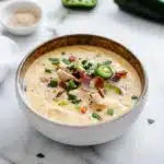 a spoon full of soup with chicken and peppers in it, being held by someone