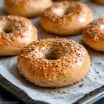 three bagels with sesame seeds and ketchup on the side text overlay reads greek yogurt protein bagels