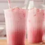 pink coconut iced latte with whipped cream and sprinkles on the side