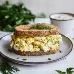 healthy high protein egg salad recipe on a plate with oranges and other food items