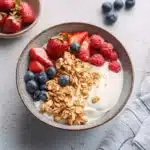a bowl filled with fruit and yogurt on top of a white tablecloth