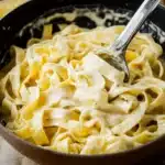 the best alfredo sauce in a pot with a wooden spoon