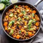 southwest sweet potato black bean and rice skillet with avocado slices on the side