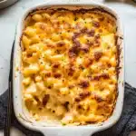creamy baked macaroni and cheese is served in a casserole dish with a serving spoon