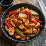 two plates filled with chicken and peppers on top of rice