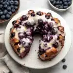 a blueberry monkey bread is on a plate with white icing and drizzled
