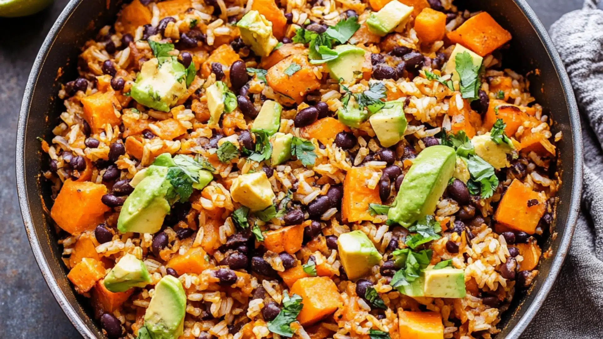 southwest sweet potato black bean and rice skillet with avocado slices on the side