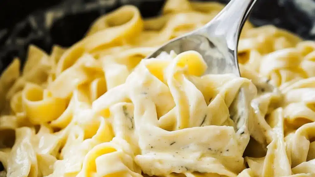 the best alfredo sauce in a pot with a wooden spoon