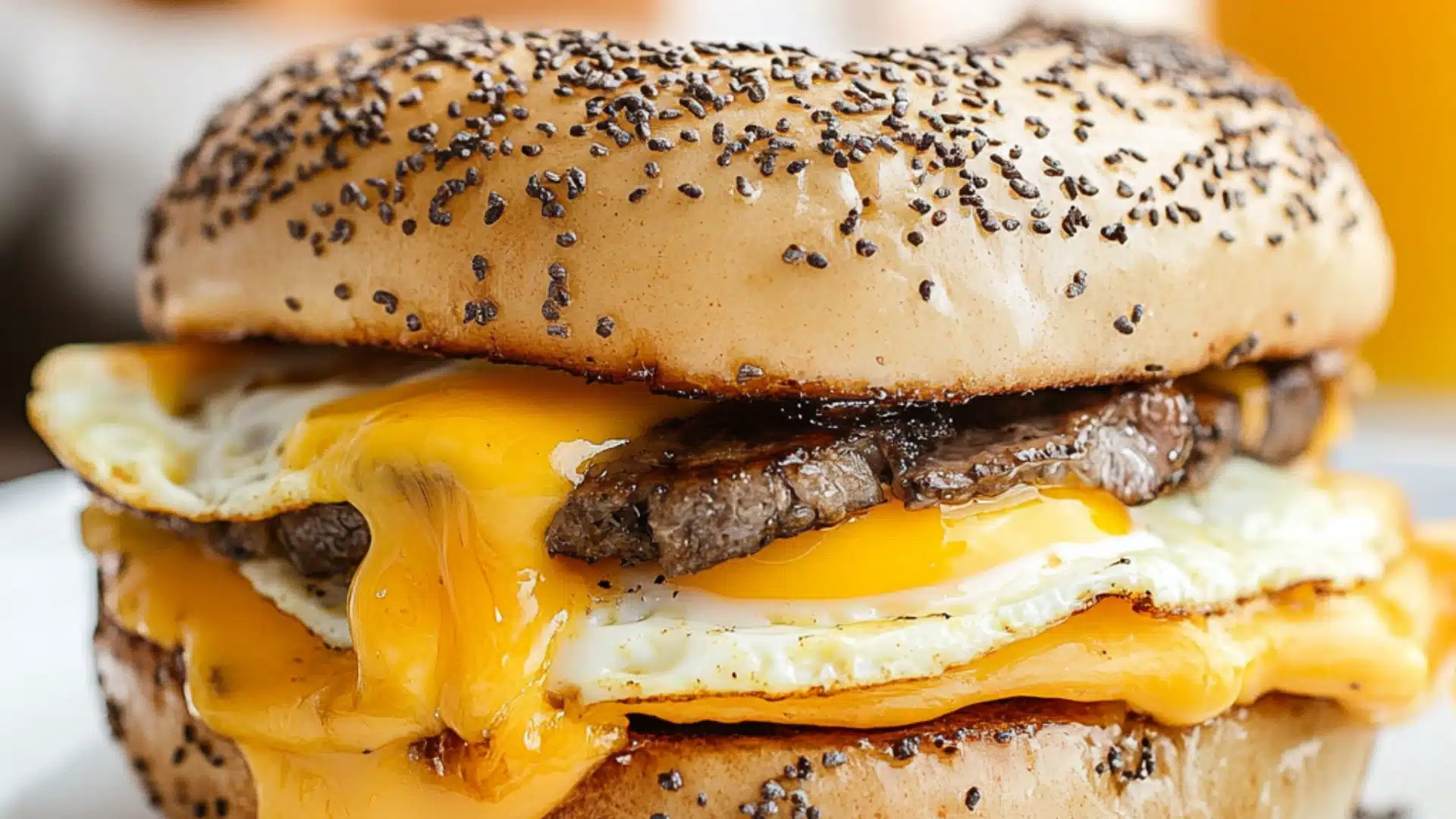 steak egg and cheese bagel sandwich on a wooden cutting board with text overlay that reads steak egg and cheese bagel sandwich