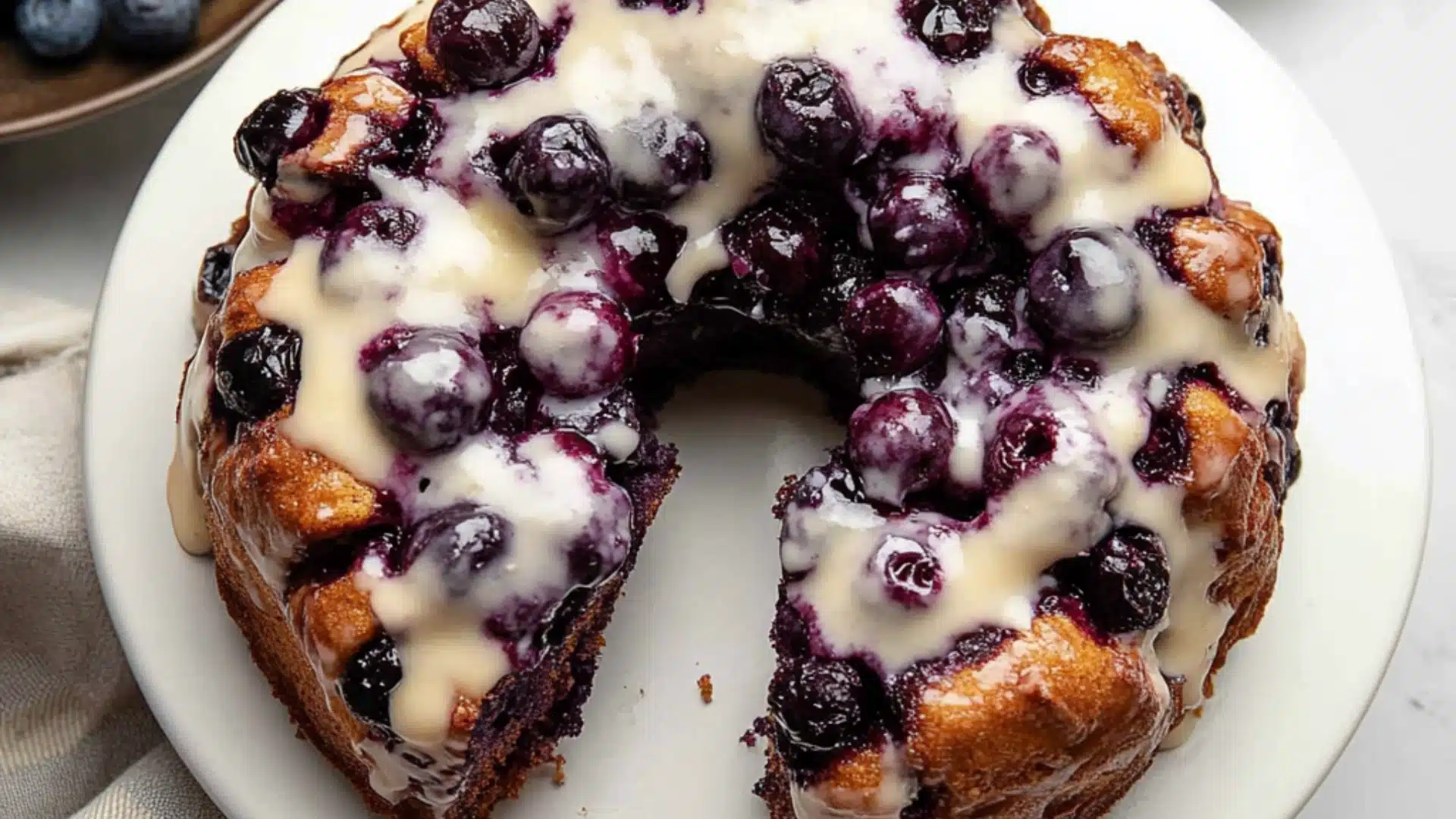 a blueberry monkey bread is on a plate with white icing and drizzled