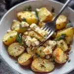greek feta baked potatoes on a white plate with text overlay that reads, greek feta baked potatoes one pot potato side dish