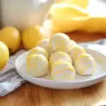 lemon truffles on a white plate with lemons in the background and text overlay
