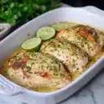 a casserole dish filled with chicken and topped with parsley next to a bottle of prima kitchen avocado lime baked chicken