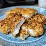 air fryer parmesan crusted chicken on a plate with sauce and herbs