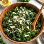 lemon parm kale salad on a white plate with spoons next to it