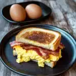 a grilled egg and bacon sandwich stacked on top of each other with parsley