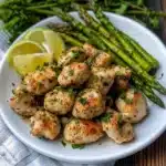 chicken and asparagus in a skillet with lemon wedges