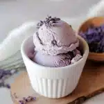 lavender ice cream in a white bowl with green leaves on top and the words lavender ice cream