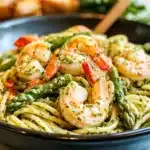 a pasta dish with shrimp, broccoli and tomatoes being stirred with a fork