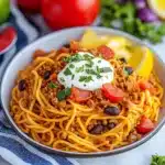 two bowls filled with taco spaghetti and topped with cheese