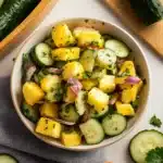 pineapple cucumber salad in two white bowls with green lettering on the side