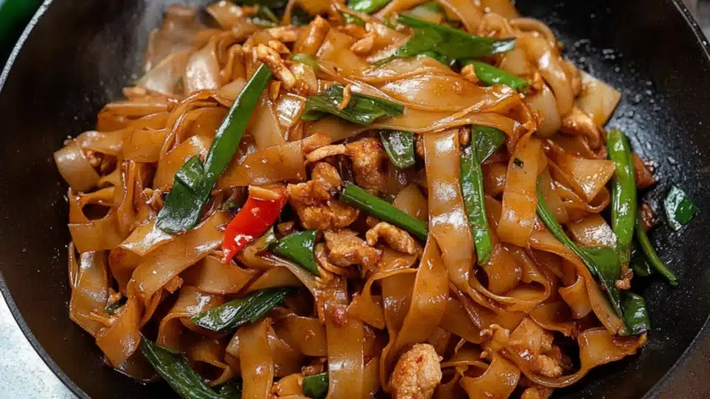two pictures of stir fry noodles with chicken, peppers and green onions in a skillet