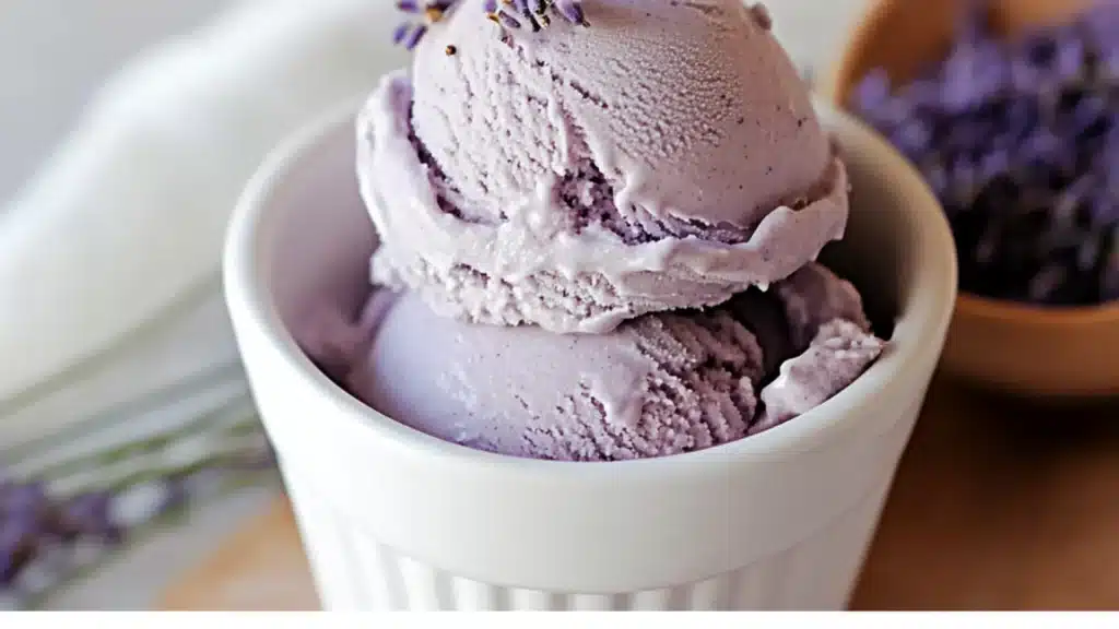lavender ice cream in a white bowl with green leaves on top and the words lavender ice cream